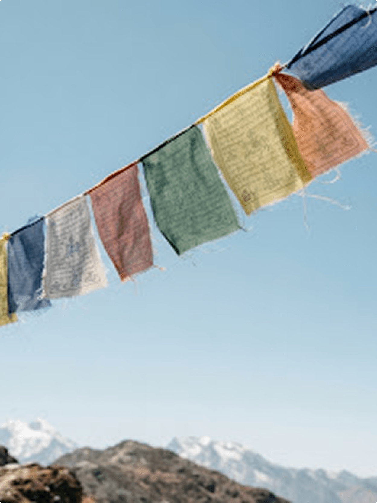 Prayer flags strung against a clear sky above the mountains